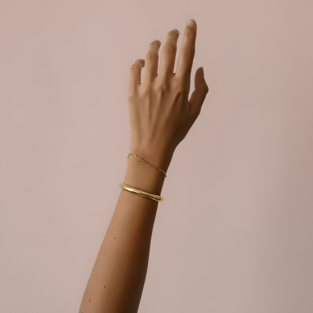 Arm met gouden armband – lichtroze achtergrond