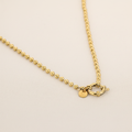 Gouden kogelketting lichtere taupe achtergrond
